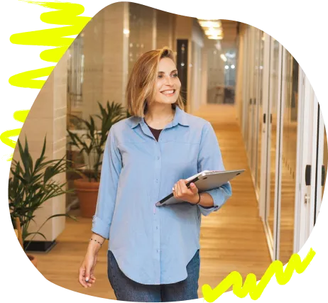 Frau mit Tablet lächelt in einem Bürogang